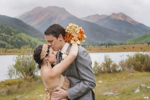 Groom kissing brides' forehead beneath Red Mountain, Colorado
