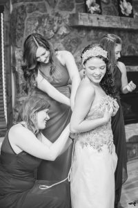 Bride with her bridesmaids lacing up her wedding dress