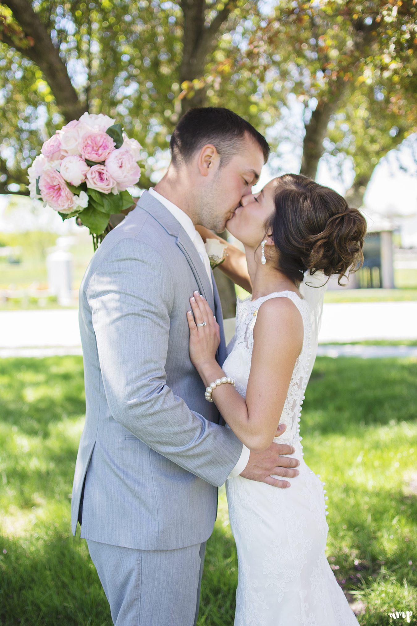 Bride and groom kissing in the shade of a tree