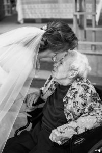 Bride kissing her grandmother in a wheel chair