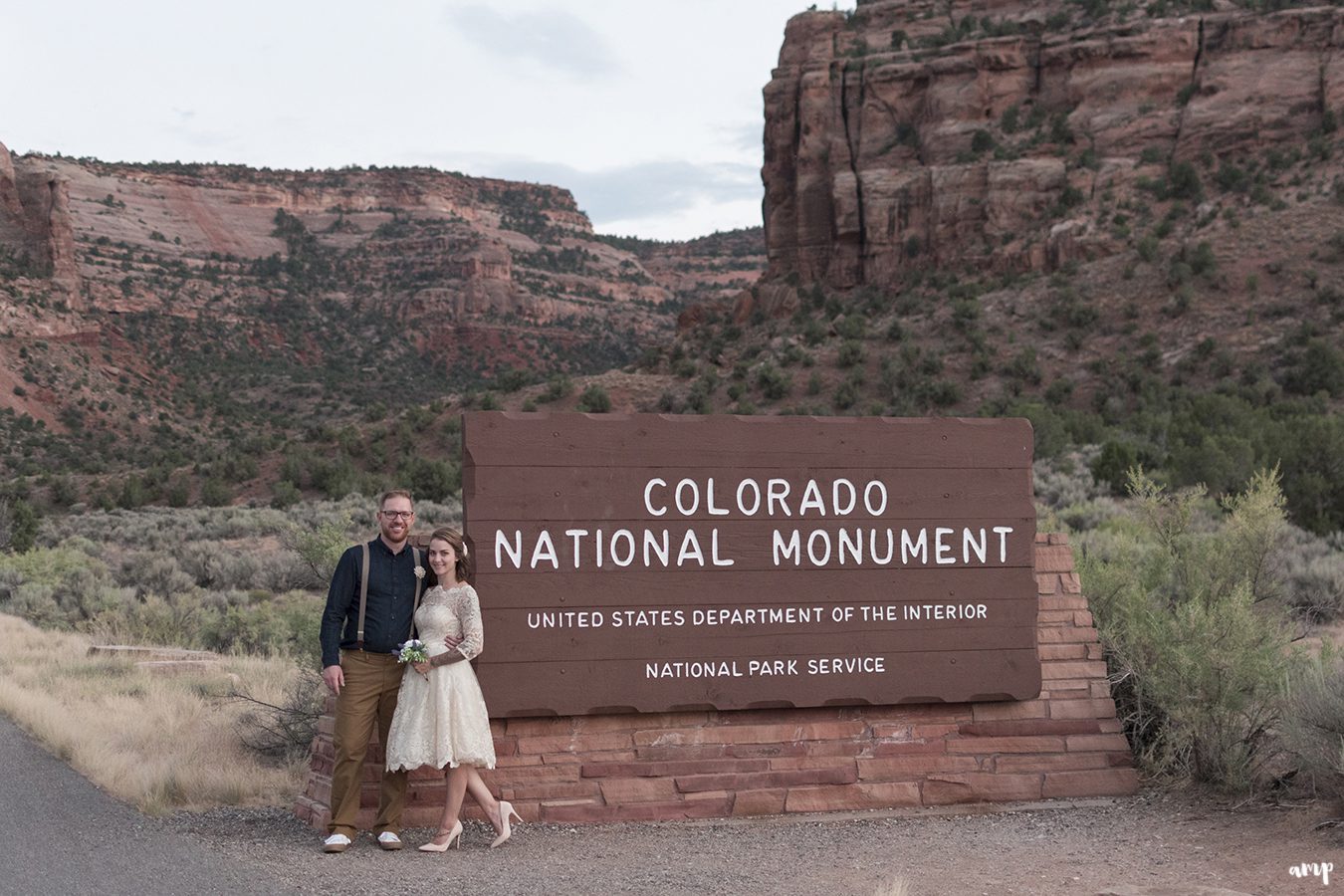 Bride and groom pose with the Colorado National Monument sign