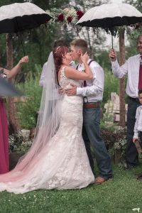 Bride and groom's first kiss in the rain