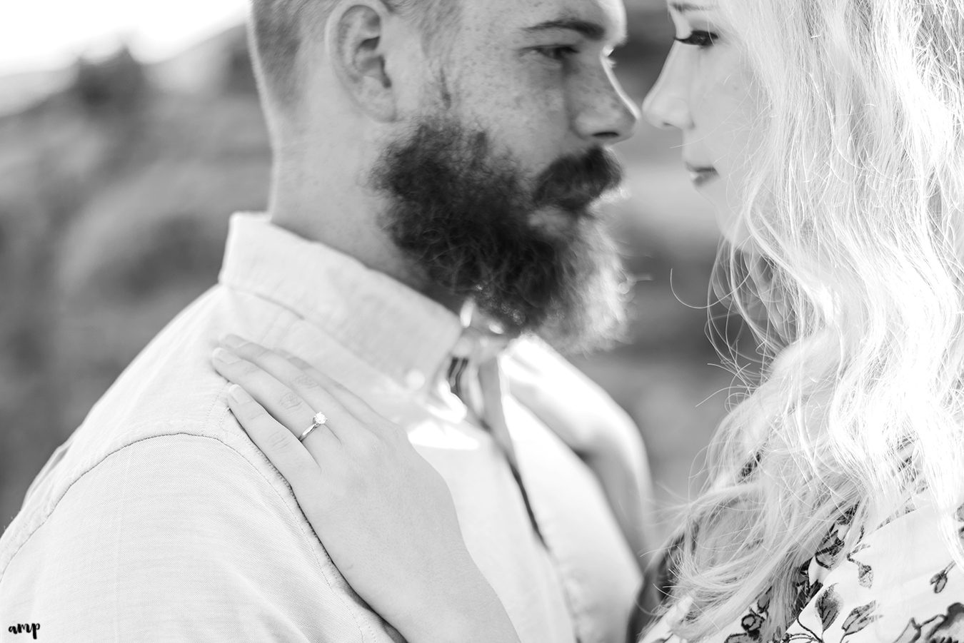 Black and white photo focused on the engagement ring as couple cuddles