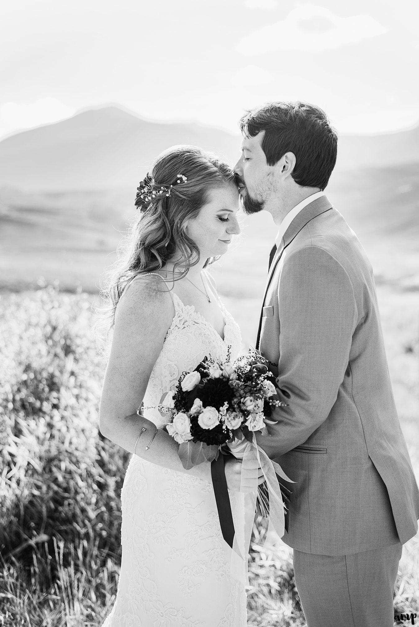 Black and white image of groom kissing his bride's forehead