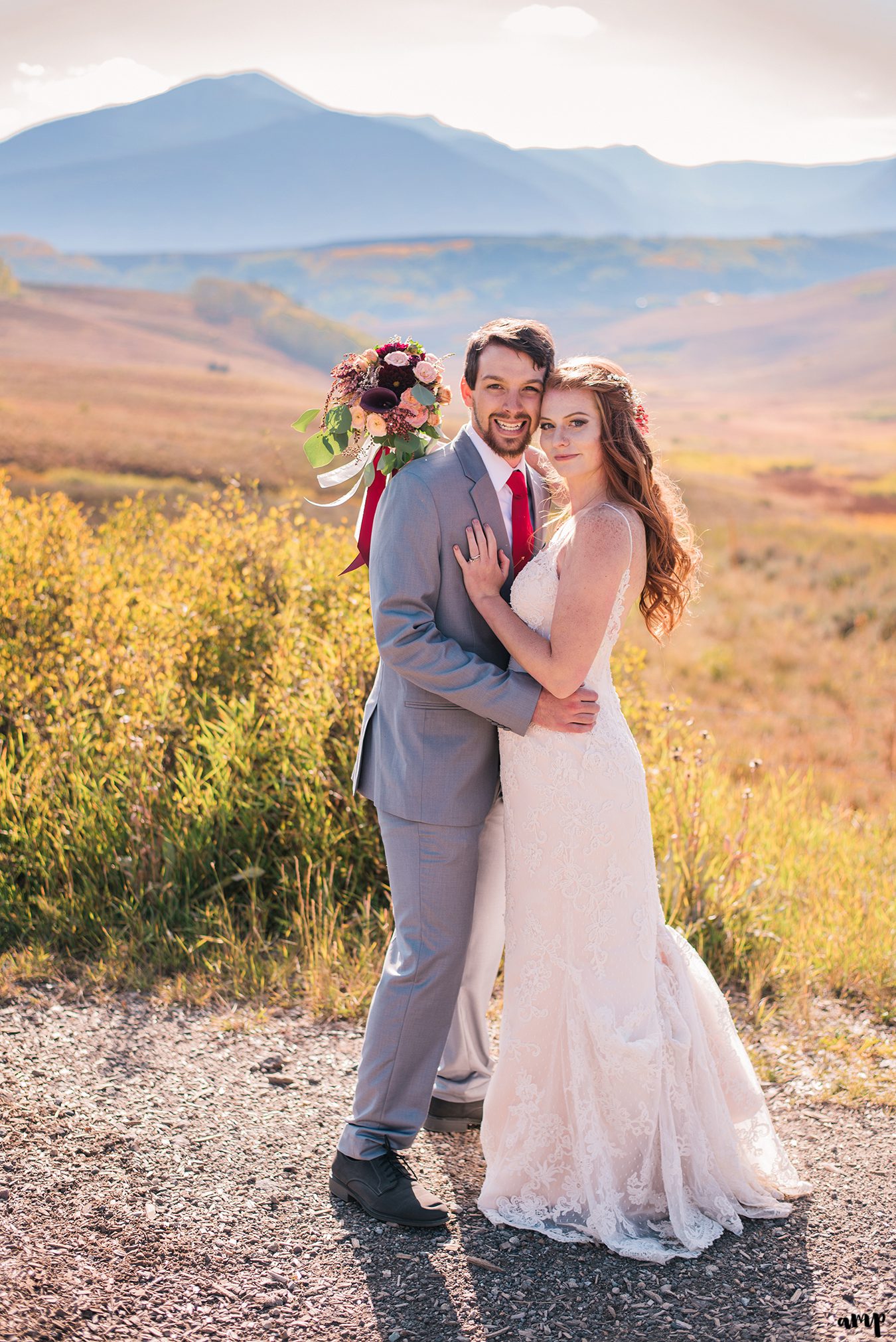 Bride and groom snuggling among the fall colors with mountains in the background