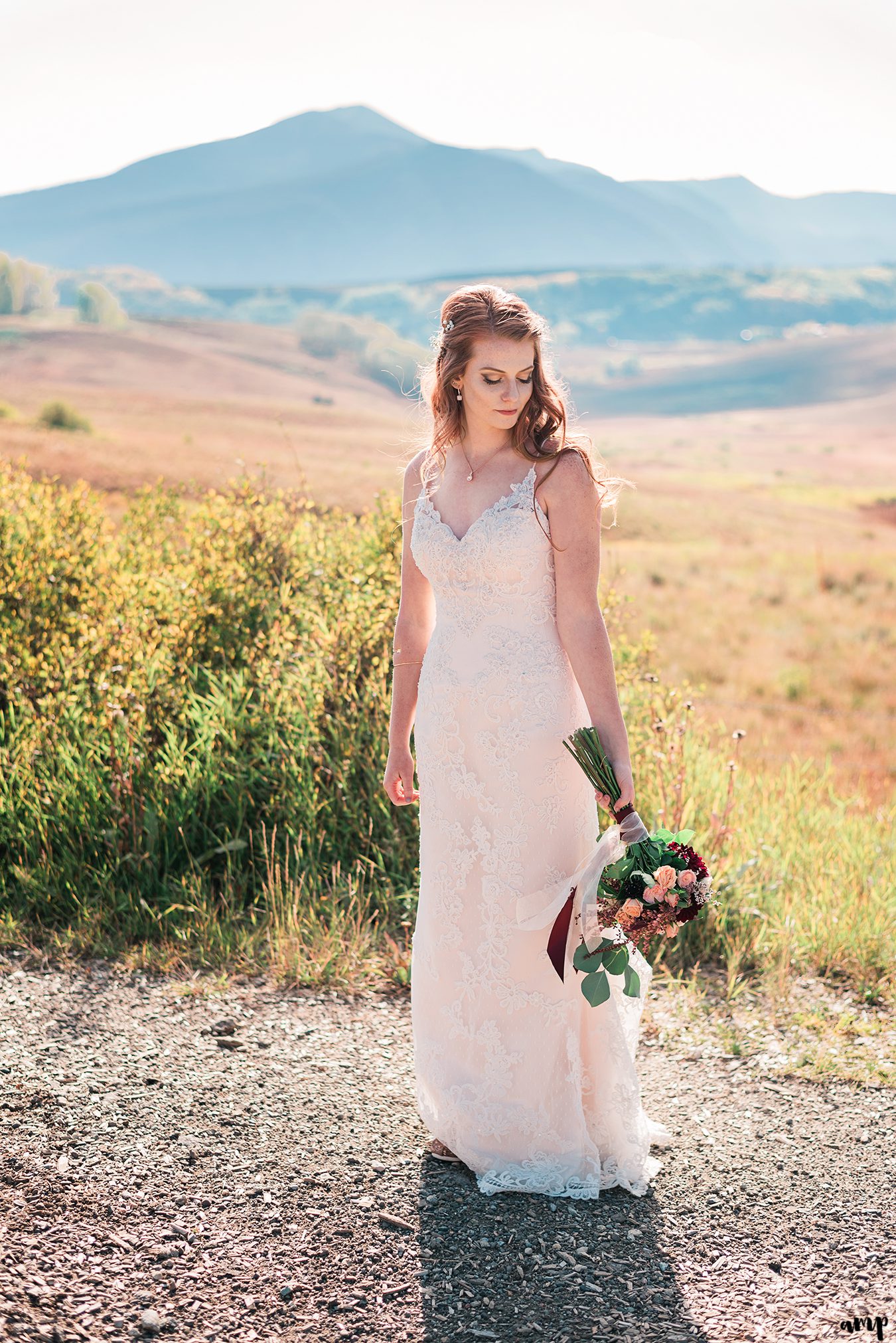 Bride gazing at her bouquet among the fall colors with mountains in the background