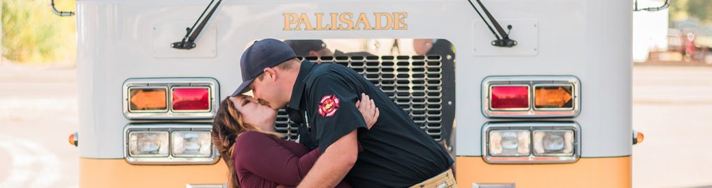Couple being dipped for a kiss in front of a fire truck
