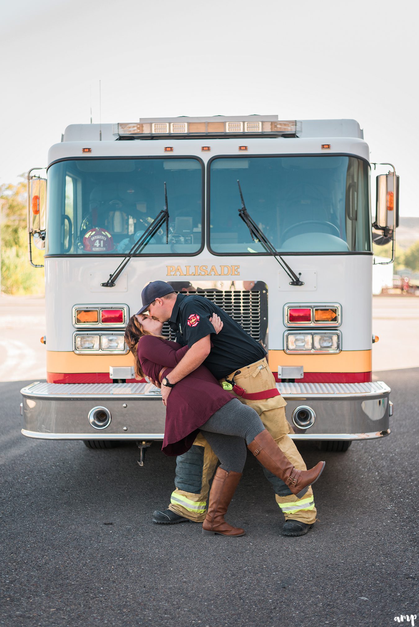 Couple being dipped for a kiss in front of a fire truck