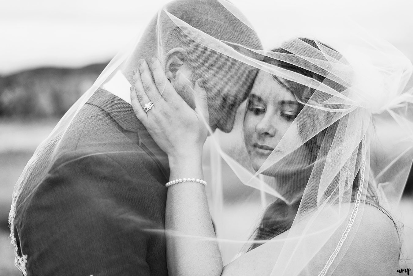 Bride and groom snuggle under her veil