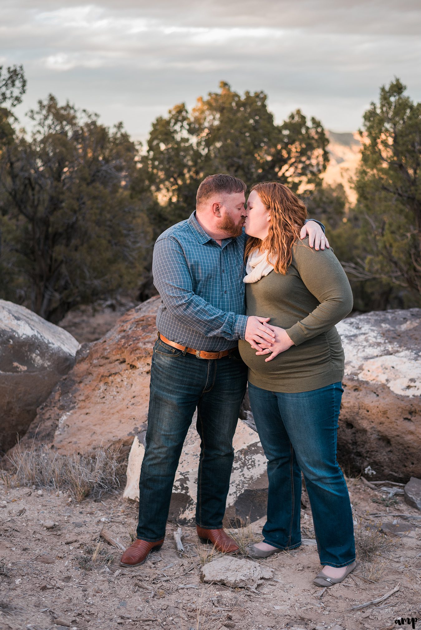 Husband and pregnant wife kiss with hands on baby bump