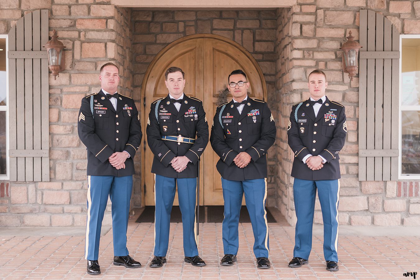 Groomsmen dressed in Army blues pose in front of the doorway of the vineyard at Two Rivers Winery