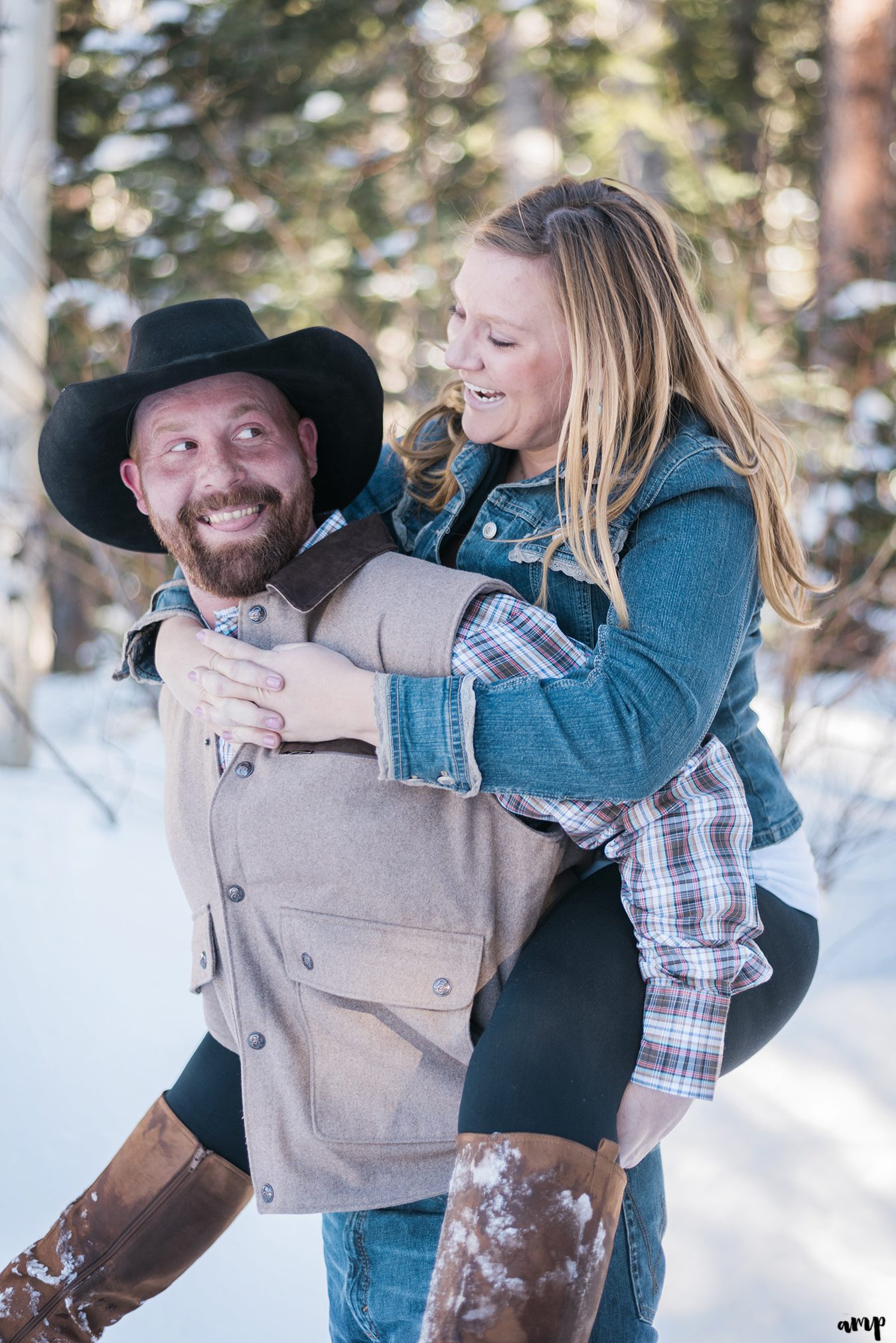Engaged couple in piggy back ride laughing at each other
