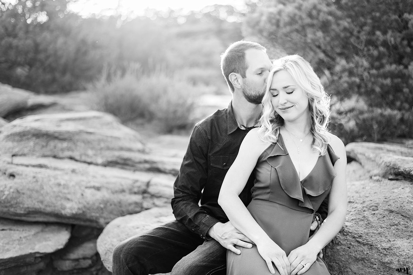 Dylan kissing Lexi's forehead while they cuddle on a rock during their engagement on the Colorado National Monument