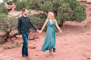 Dylan and Lexi walk hand-in-hand through the juniper trees of the Colorado National Monument for their engagement photos
