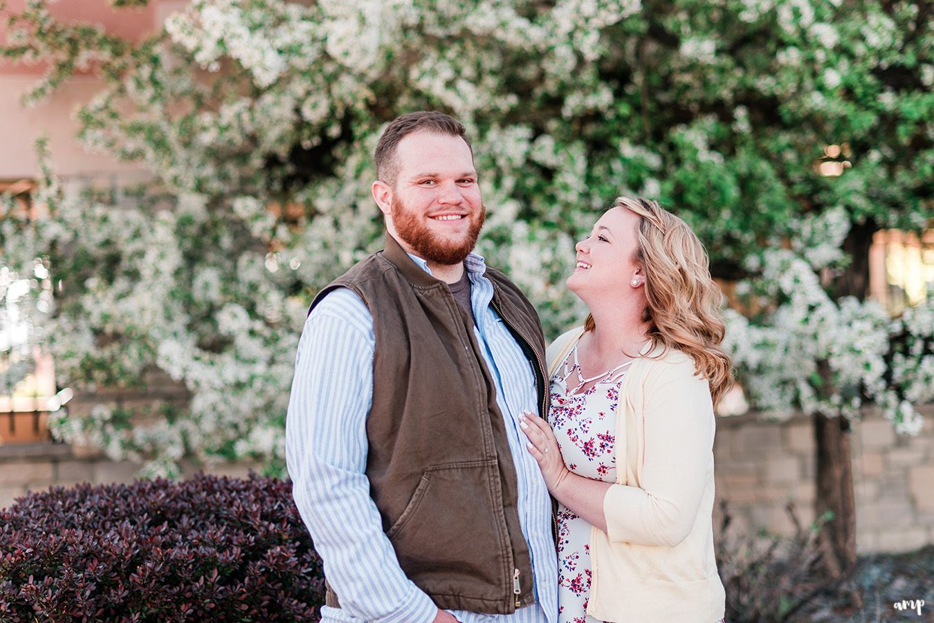 Ben and Dessa laughing together in front of a blooming tree in Downtown Grand Junction