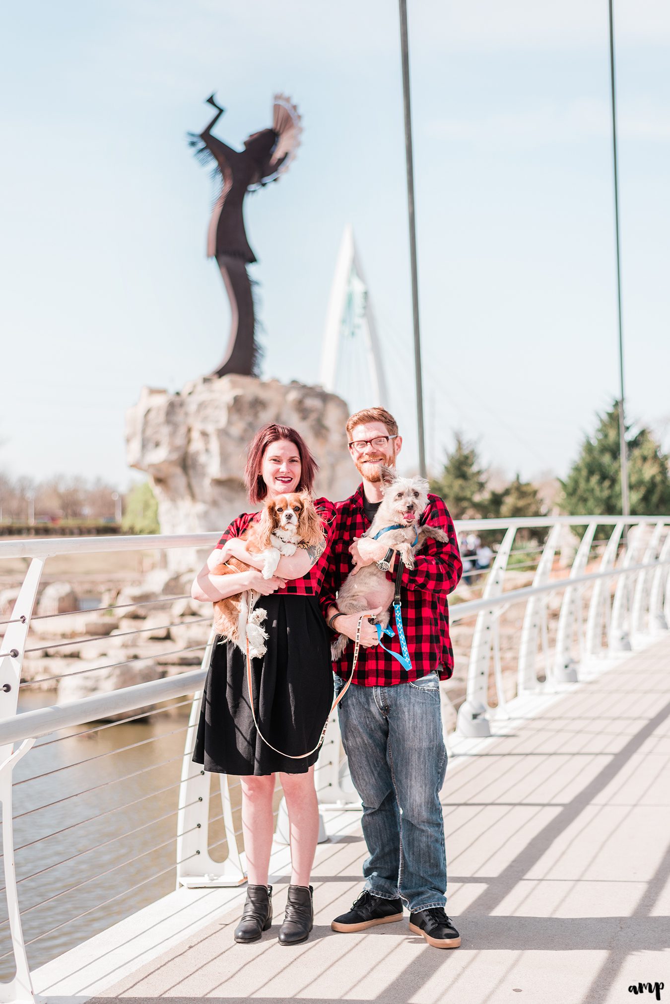 Ben and Courtnee holding their dogs in front of the Keeper of the Plains