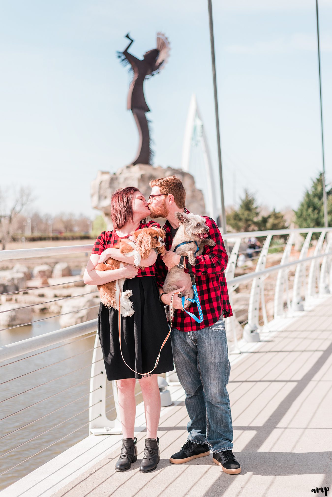 Ben and Courtnee holding their dogs in front of the Keeper of the Plains