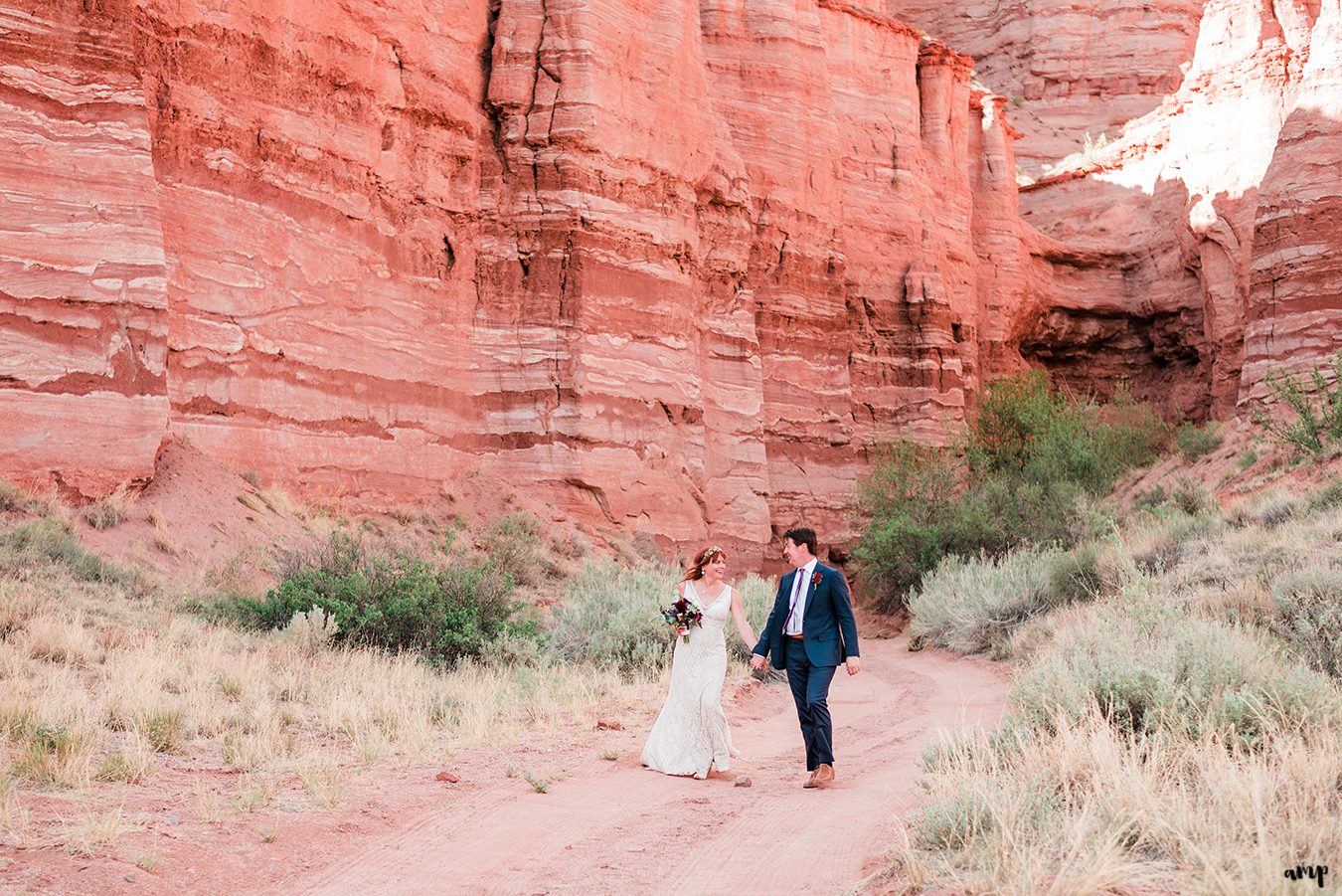 Blake and Carrie walk hand-in-hand under the Palisade of Gateway Canyons