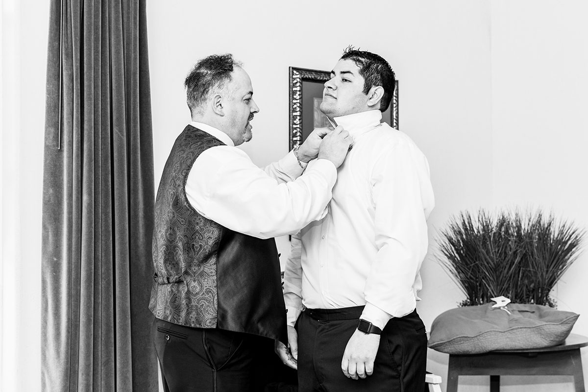 Groom getting ready with his dad helping tie his tie
