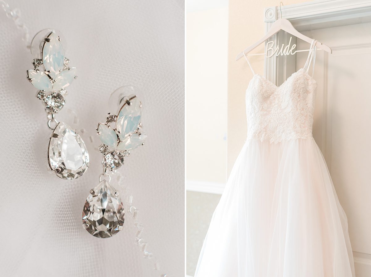 The bride's dangly earrings and her dress hanging in the hotel hallway