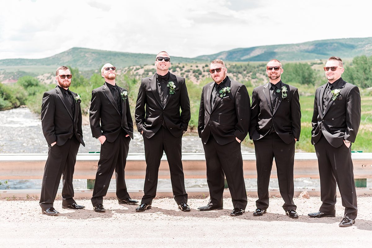 The groomsmen on a bridge with river and mountains in the background
