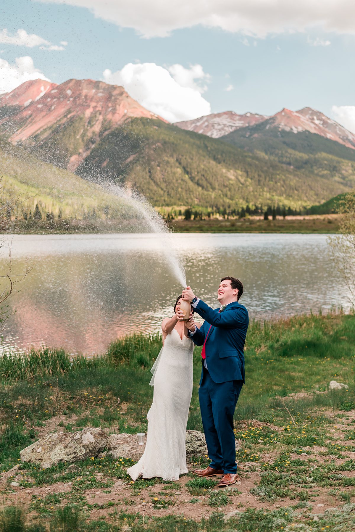 andrea and mckade spray champagne beside the lake