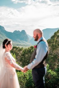 Katrina and Frank hold hands while the mountains in the background are in focus