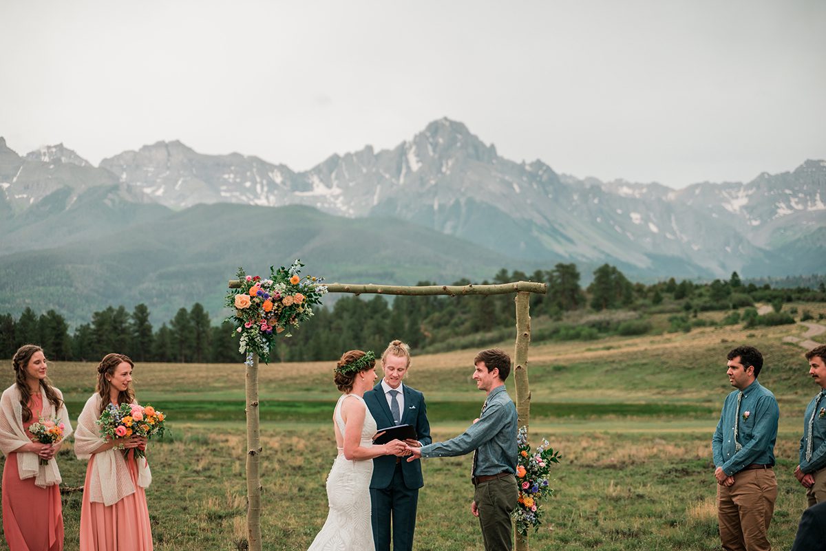 Tom and Sarah exchange rings with large mountains behind them