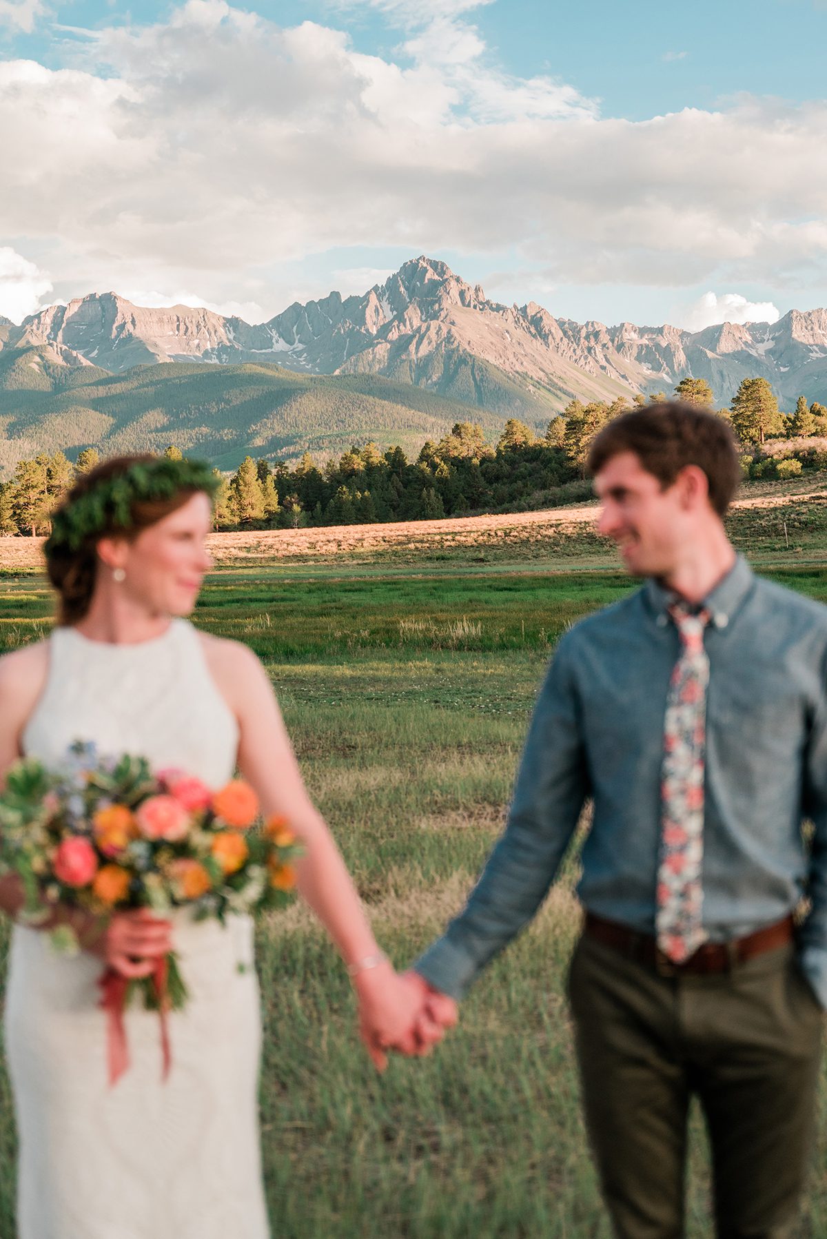 Sarah & Tom hold hands while the image is focused on the mountains behind them