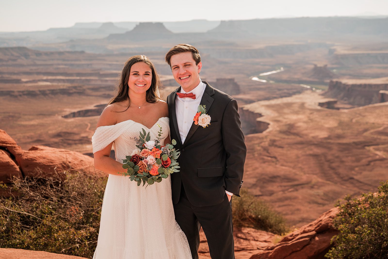 Newlywed couple smiling at Green River Overlook, eloping in Canyonlands National Park