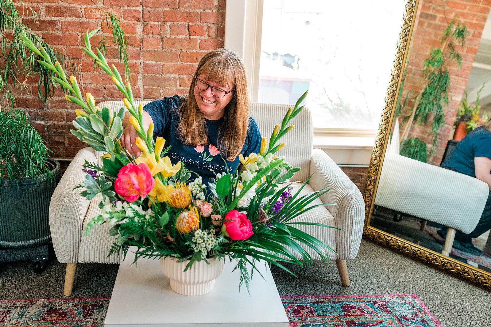 Florist Sydney arranging stems in a clay vase, hands visible mid-arrangement, natural light